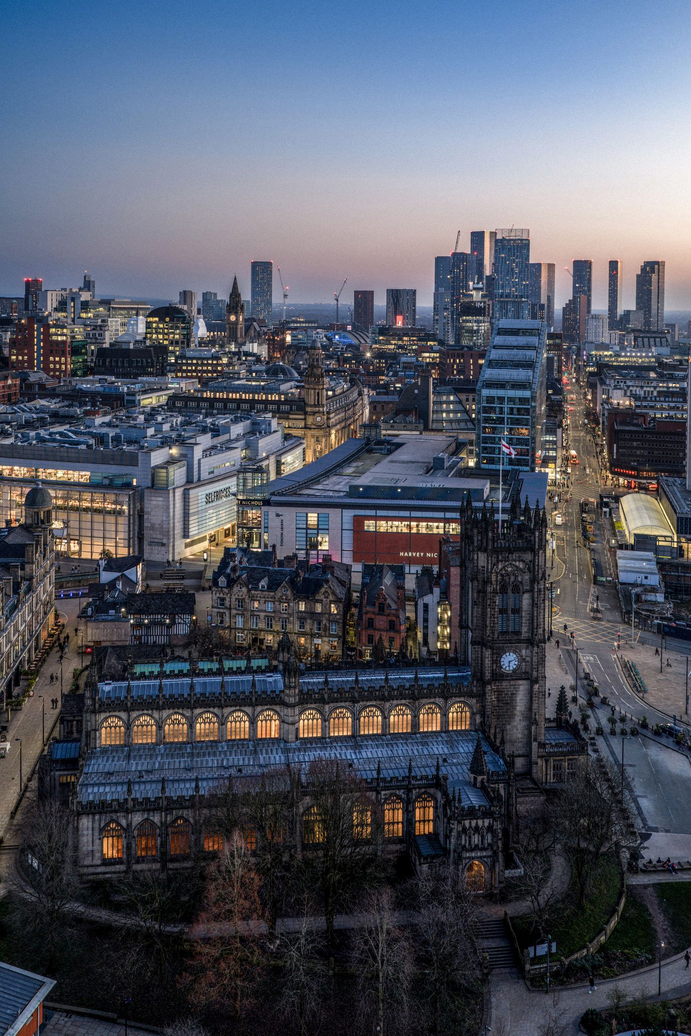 Manchester Cathedral en de skyline van Manchester bij valavond